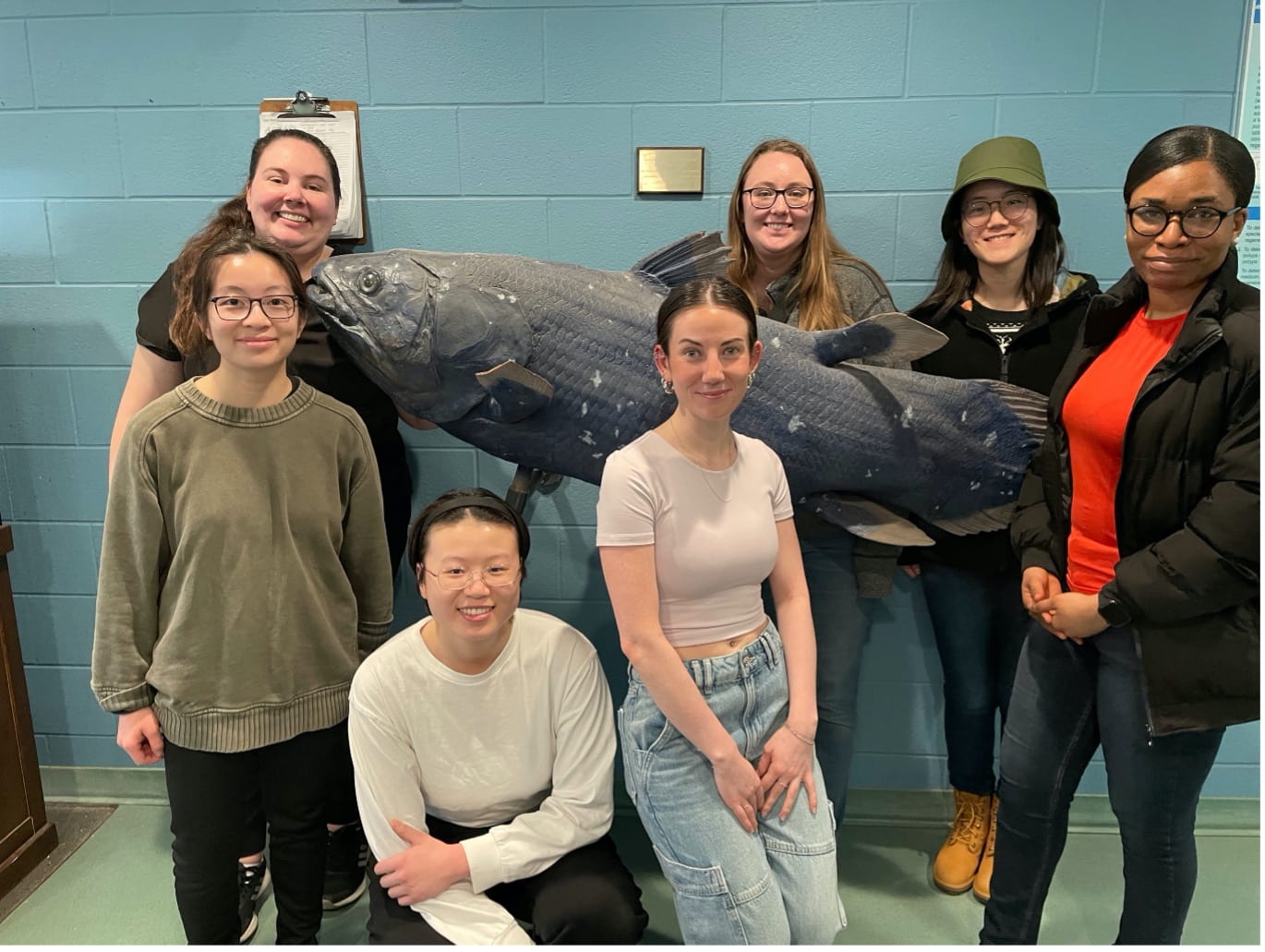 Picture of CCSAW Student Chapter tour group at the Hagen Aquaculture lab with a model of a coelacanth fish.
